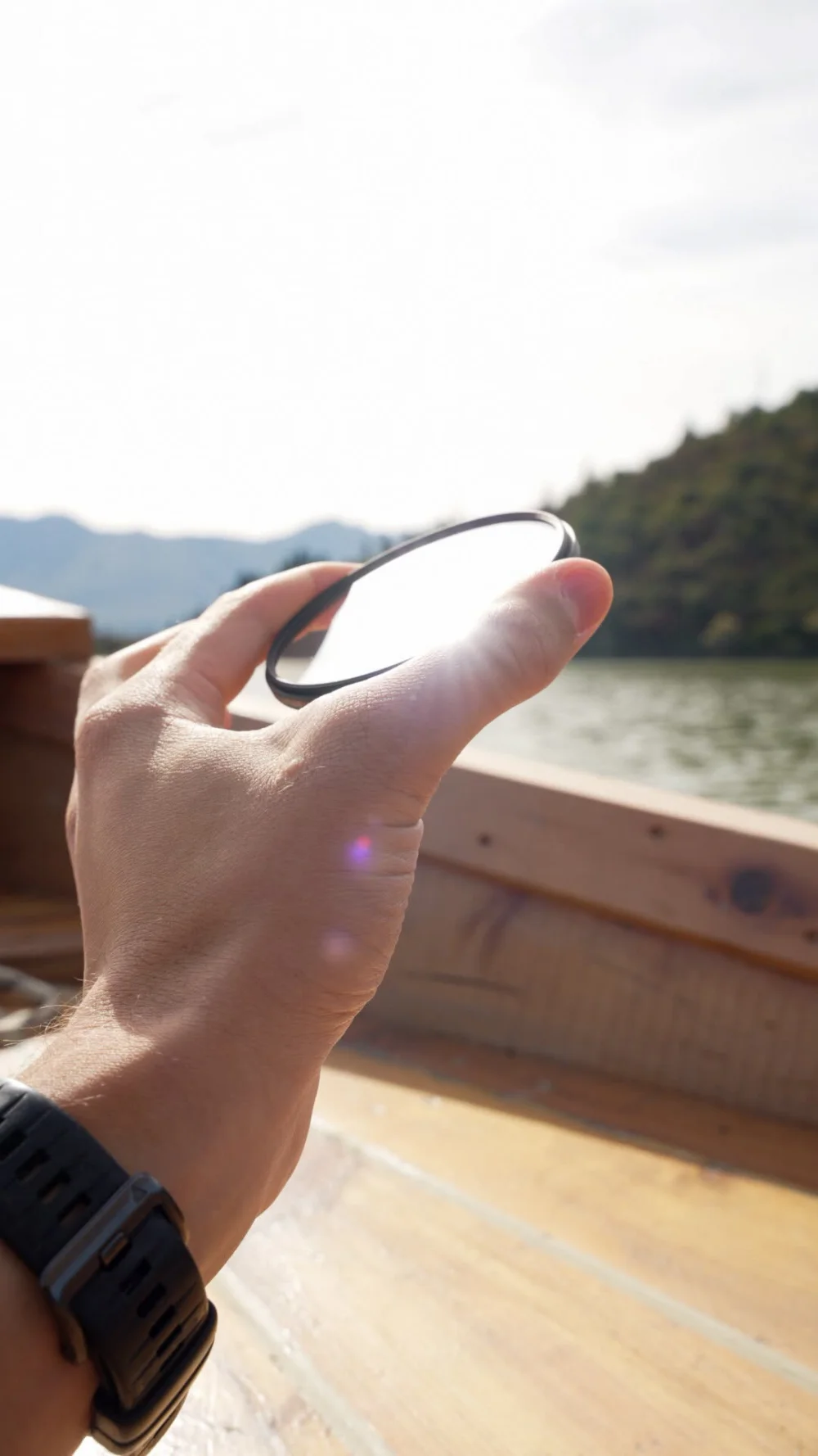 Marumi PRIME II Lens Protect – ochrona obiektywu w nowym wydaniu zdjęcie przedstawiające filtr Marumi Prime II Lens Protect w dłoni fotografa z odbijającymi się od jego powierzchni promieniami światła słonecznego